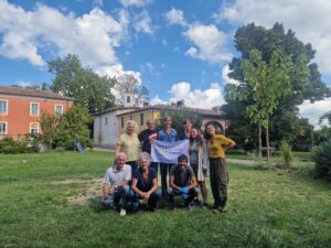 A group photo of the EStà team in a garden holding a banner with the organisation's logo